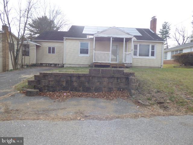 view of front facade featuring solar panels, a porch, and a front yard