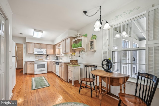 kitchen featuring light wood-type flooring, white appliances, light brown cabinets, decorative light fixtures, and a chandelier