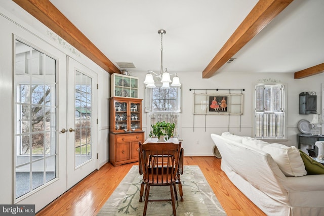 dining space featuring beam ceiling, light hardwood / wood-style floors, french doors, and a chandelier