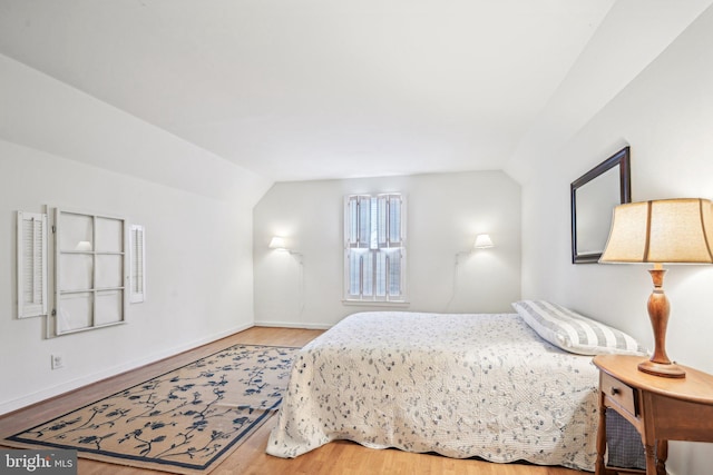 bedroom with wood-type flooring and vaulted ceiling