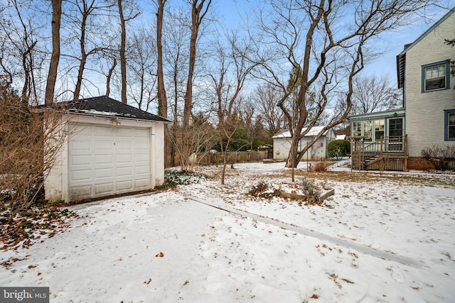 snowy yard featuring a garage and an outdoor structure