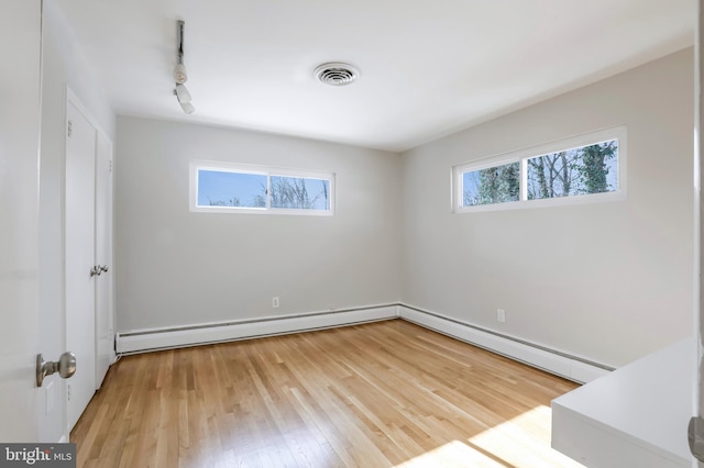 unfurnished room with a baseboard heating unit, hardwood / wood-style flooring, and a wealth of natural light