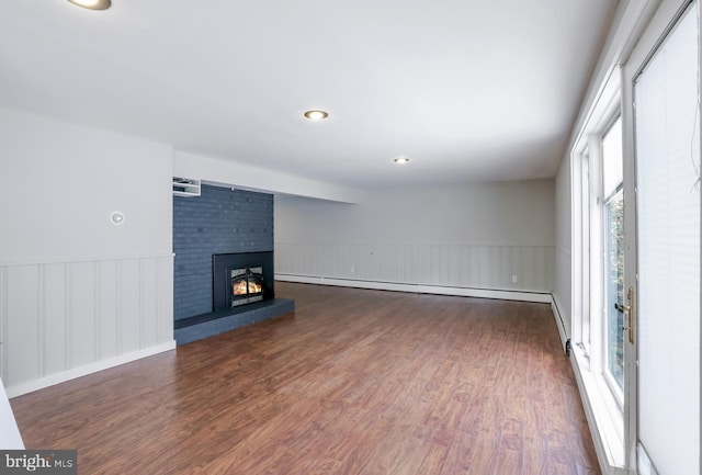 unfurnished living room featuring a baseboard radiator, dark wood-type flooring, and a fireplace