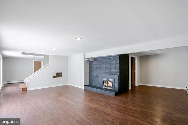 unfurnished living room with dark hardwood / wood-style flooring, a brick fireplace, and baseboard heating