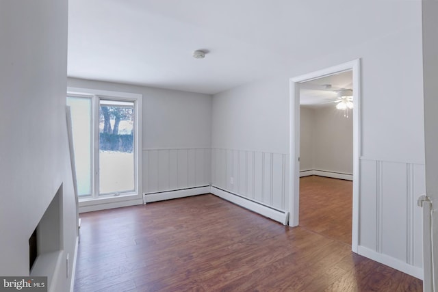 unfurnished room featuring a baseboard heating unit and wood-type flooring