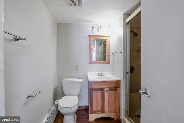 bathroom featuring vanity, a shower with door, and toilet