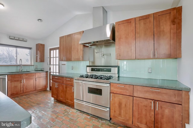 kitchen with lofted ceiling, wall chimney range hood, sink, stainless steel appliances, and decorative backsplash