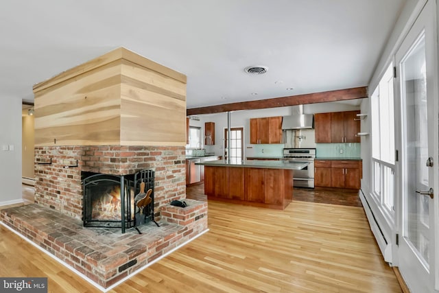 kitchen with stainless steel range, a baseboard radiator, wall chimney exhaust hood, and light wood-type flooring