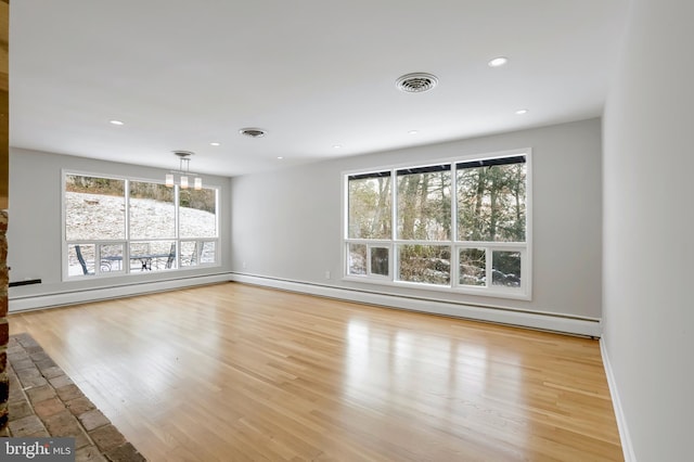 unfurnished living room featuring a baseboard radiator, a chandelier, and light hardwood / wood-style floors