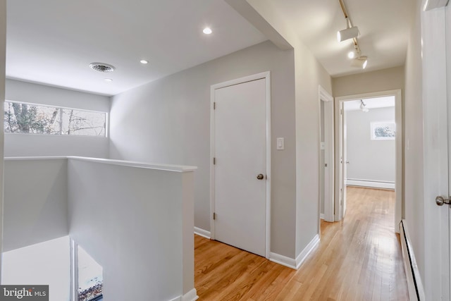 hall featuring baseboard heating, track lighting, and light hardwood / wood-style flooring