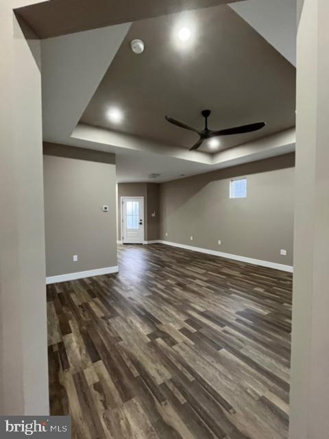 spare room with dark hardwood / wood-style flooring, a raised ceiling, and ceiling fan