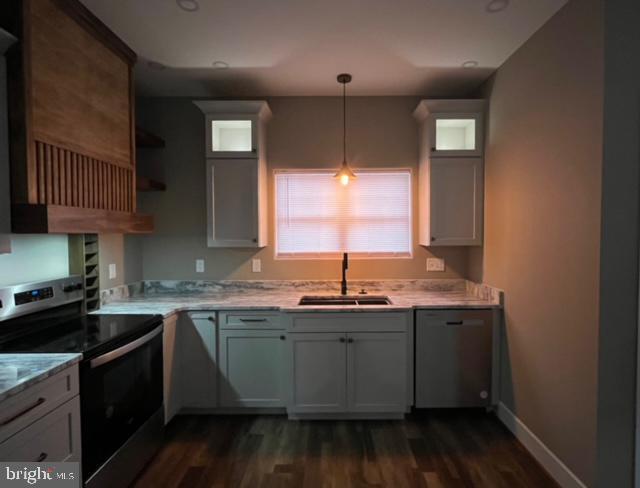 kitchen featuring appliances with stainless steel finishes, light stone counters, sink, pendant lighting, and white cabinetry