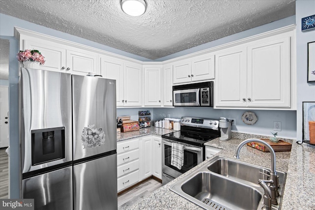 kitchen with white cabinets, appliances with stainless steel finishes, a textured ceiling, and sink