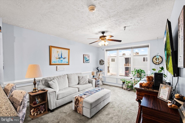 living room featuring ceiling fan, carpet floors, and a textured ceiling