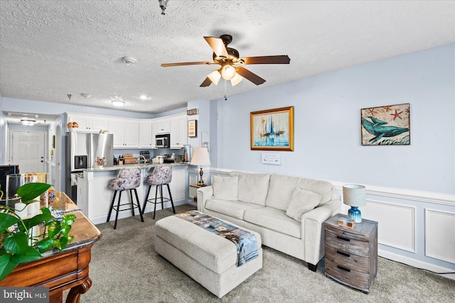 carpeted living room with ceiling fan and a textured ceiling