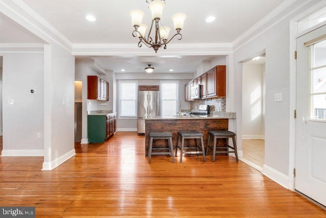 kitchen featuring kitchen peninsula, light wood-type flooring, stainless steel refrigerator, and ornamental molding