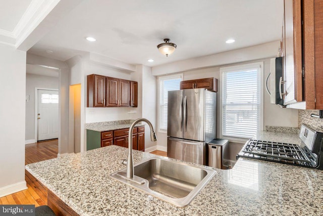 kitchen featuring kitchen peninsula, sink, light hardwood / wood-style floors, and appliances with stainless steel finishes