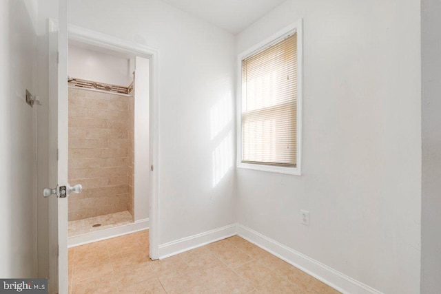 bathroom with tile patterned flooring and a tile shower