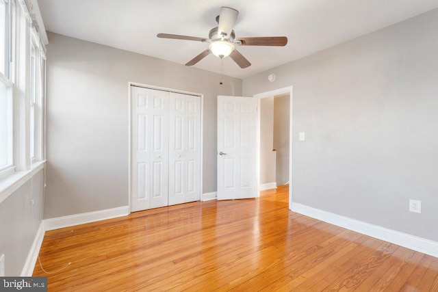 unfurnished bedroom featuring ceiling fan, light hardwood / wood-style floors, and a closet