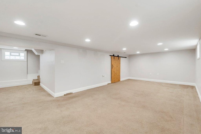 basement with a barn door and light carpet