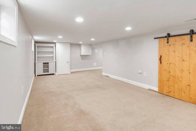 basement featuring a barn door and light colored carpet