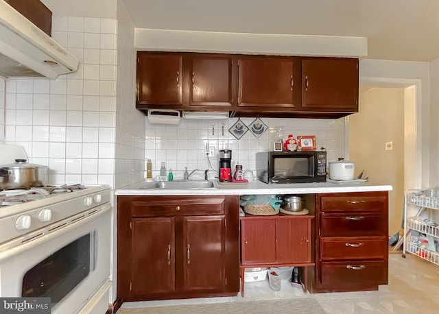 kitchen with tasteful backsplash, white gas range, sink, and range hood