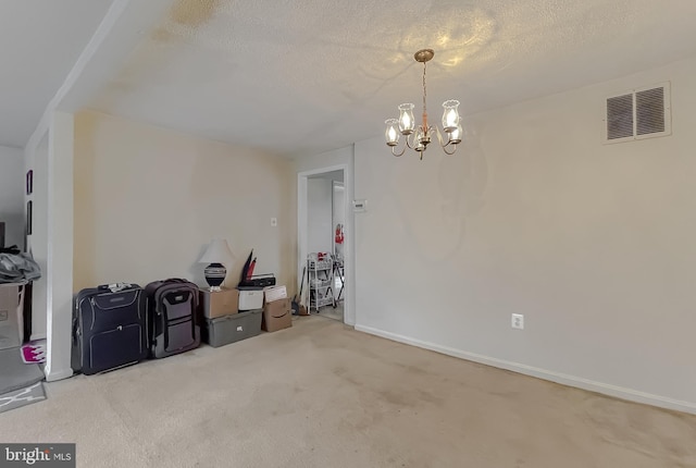 carpeted spare room with a textured ceiling and an inviting chandelier