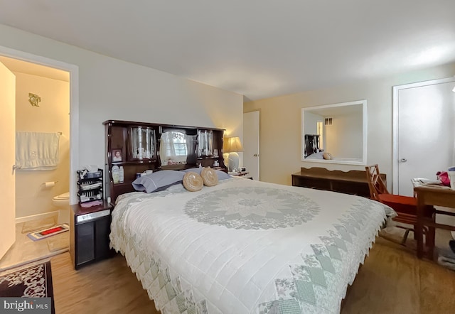 bedroom with hardwood / wood-style flooring and connected bathroom