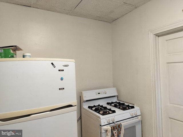 kitchen with a paneled ceiling and white appliances