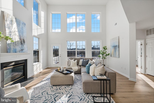 living room featuring a towering ceiling and light wood-type flooring