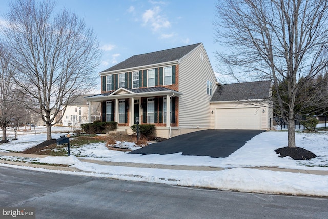 colonial-style house featuring a garage and covered porch