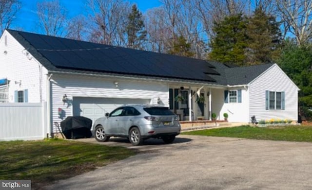 view of front of house with a garage, a front lawn, and solar panels