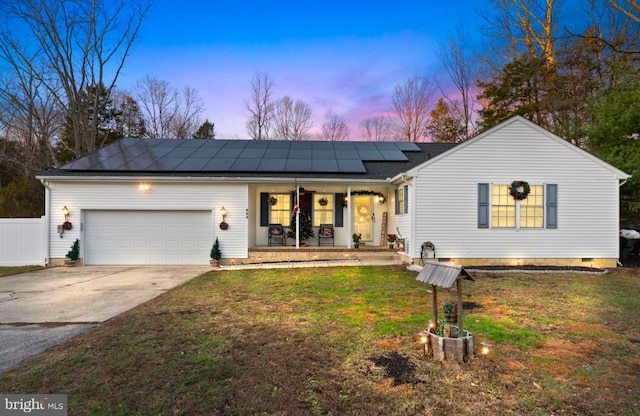 ranch-style home with a porch, a garage, a lawn, and solar panels