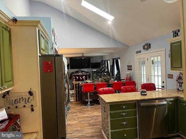 kitchen featuring vaulted ceiling, stainless steel appliances, kitchen peninsula, and green cabinets