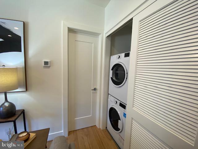 laundry area featuring stacked washer and clothes dryer and hardwood / wood-style floors