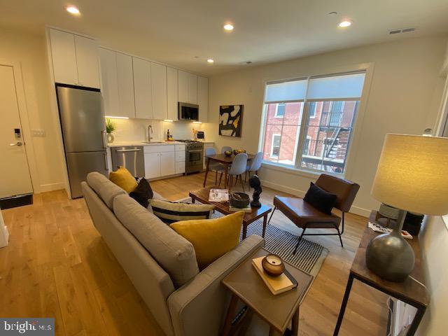 living room featuring sink and light hardwood / wood-style flooring