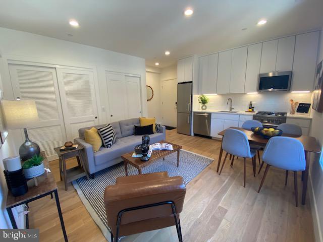 living room featuring sink and light hardwood / wood-style flooring