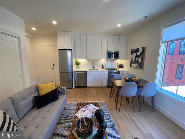 kitchen featuring white cabinets, light wood-type flooring, and appliances with stainless steel finishes