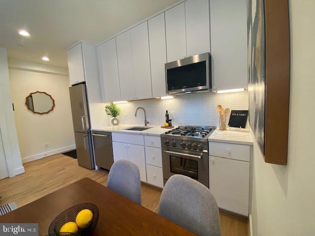 kitchen featuring sink, white cabinets, tasteful backsplash, light hardwood / wood-style flooring, and high end appliances