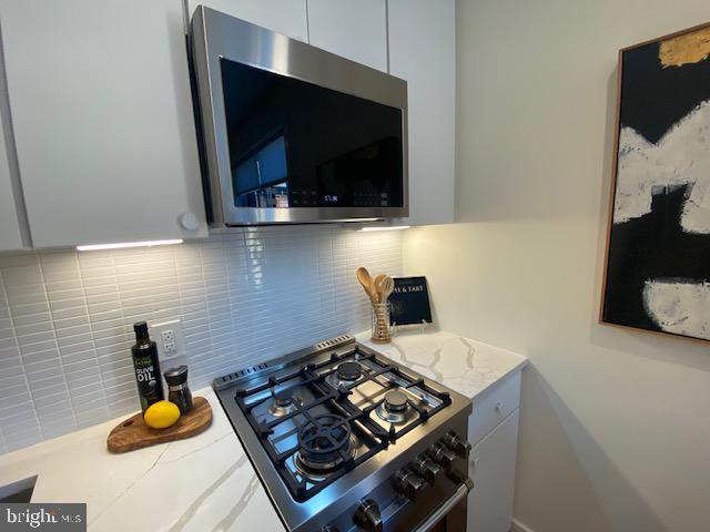 kitchen featuring white cabinets, appliances with stainless steel finishes, and decorative backsplash