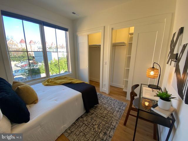 bedroom with a walk in closet, hardwood / wood-style floors, and a closet