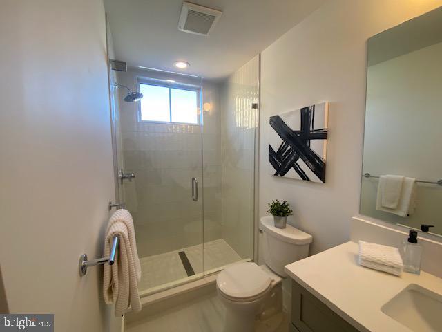 bathroom with an enclosed shower, vanity, and toilet