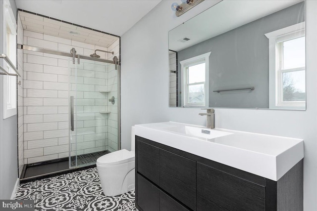 bathroom with vanity, toilet, a shower with door, and a healthy amount of sunlight