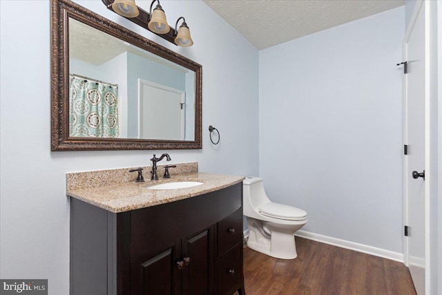 bathroom with hardwood / wood-style flooring, vanity, toilet, and a textured ceiling