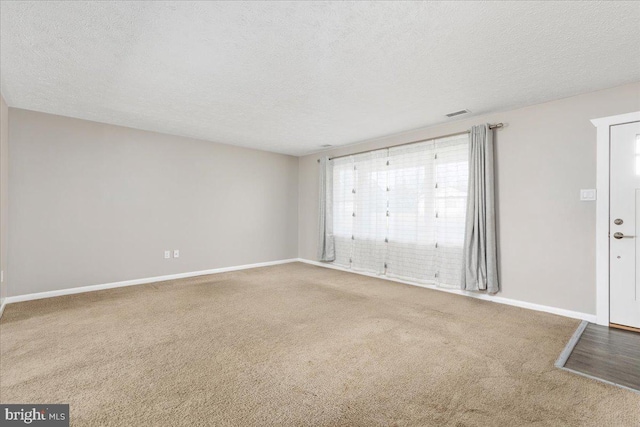 unfurnished room with carpet and a textured ceiling