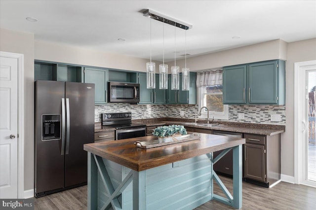 kitchen with pendant lighting, a center island, sink, and stainless steel appliances