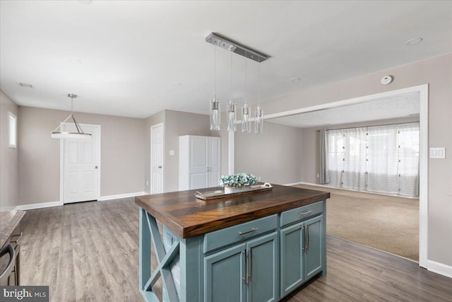 kitchen with butcher block countertops, a kitchen island, hanging light fixtures, and a healthy amount of sunlight