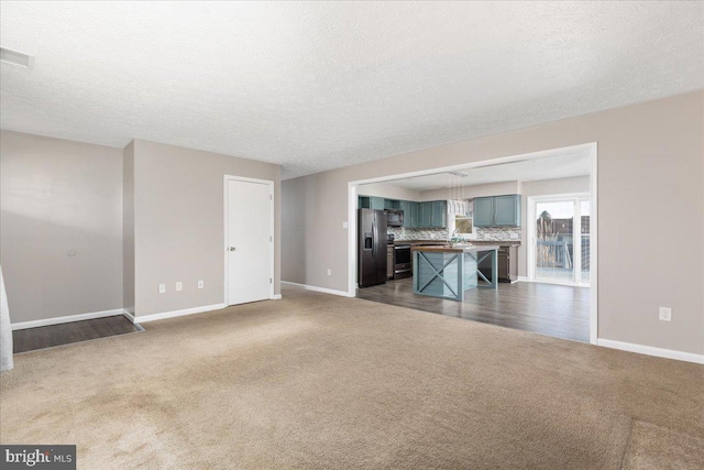 unfurnished living room with dark carpet and a textured ceiling