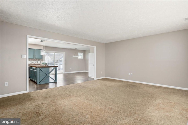 unfurnished living room featuring dark carpet and a textured ceiling