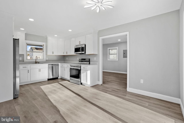 kitchen with white cabinetry, sink, stainless steel appliances, and light hardwood / wood-style floors